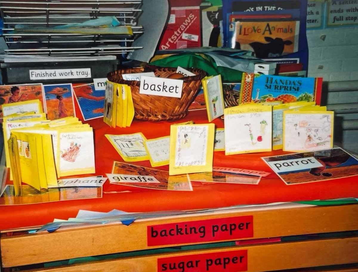 A classroom resource display based on the story Handa's Surprise, featuring handmade mini books, word cards, and a woven basket.