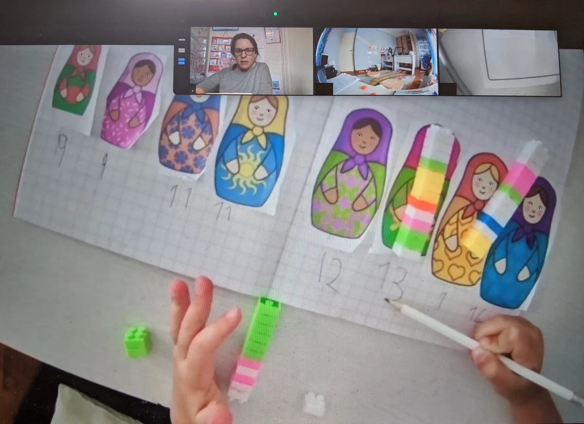 A computer screen showing an online maths lesson where a child orders and measures paper images of Russian dolls using colorful linking cubes.