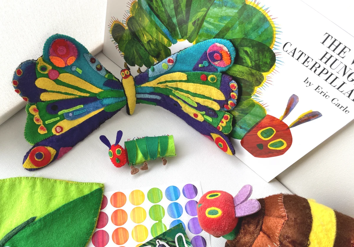 Alt text options      Short option: Handmade felt props—including a butterfly, caterpillar, cocoon, and leaf—displayed alongside the picture book The Very Hungry Caterpillar.
